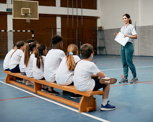 Gym instructor explaining posture and movement to a group of children